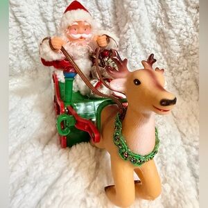 Vintage Santa Claus in a green sleigh with a reindeer collectible toy.